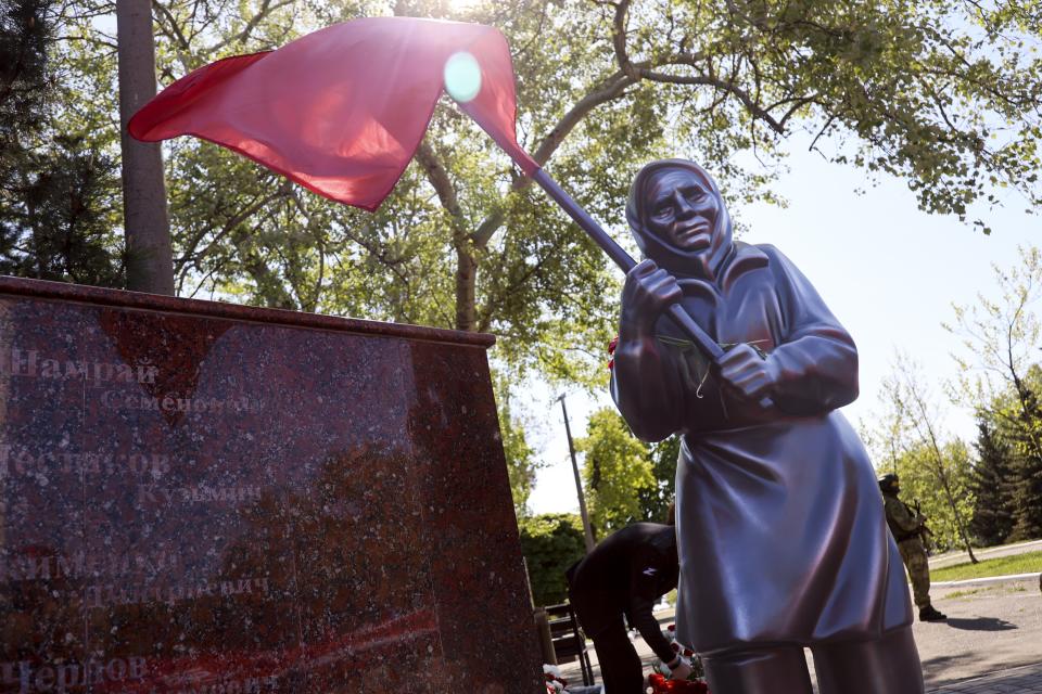A sculpture of Ukrainian woman holding a Soviet-era red flag is seen during celebration of the 77th anniversary of the end of World War II in Mariupol, in territory under the government of the Donetsk People's Republic, eastern Ukraine, Monday, May 9, 2022. (AP Photo/Alexei Alexandrov)