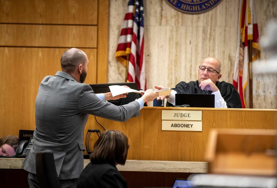 Assistant State Attorney Mark Levine hands Judge J. Kevin Abdoney a folder of crime scene photos Tuesday, during the second day of Marcell Waldon's trial. On Wednesday, more prosecution witnesses talked about the crime scene, a burned out Audi that belonged to one of the victims and text messages shared between Waldon and another man the day of the killings.