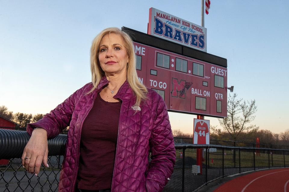 Regina Mullen, mother of Kyle Mullen, who died following Navy SEAL training last year, stands in front of the scoreboard on the football field, where an image of her son's jersey hangs, at Manalapan High School in Manalapan, NJ Monday, January 30, 2023. 