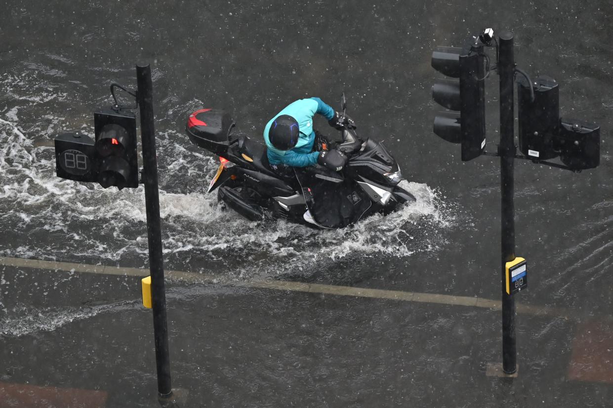 A motorcyclist tries to ride through deep water on a flooded road in The Nine Elms district of London on July 25, 2021 during heavy rain. - Buses and cars were left stranded when roads across London flooded on Sunday, as repeated thunderstorms battered the British capital. (Photo by JUSTIN TALLIS / AFP) (Photo by JUSTIN TALLIS/AFP via Getty Images)
