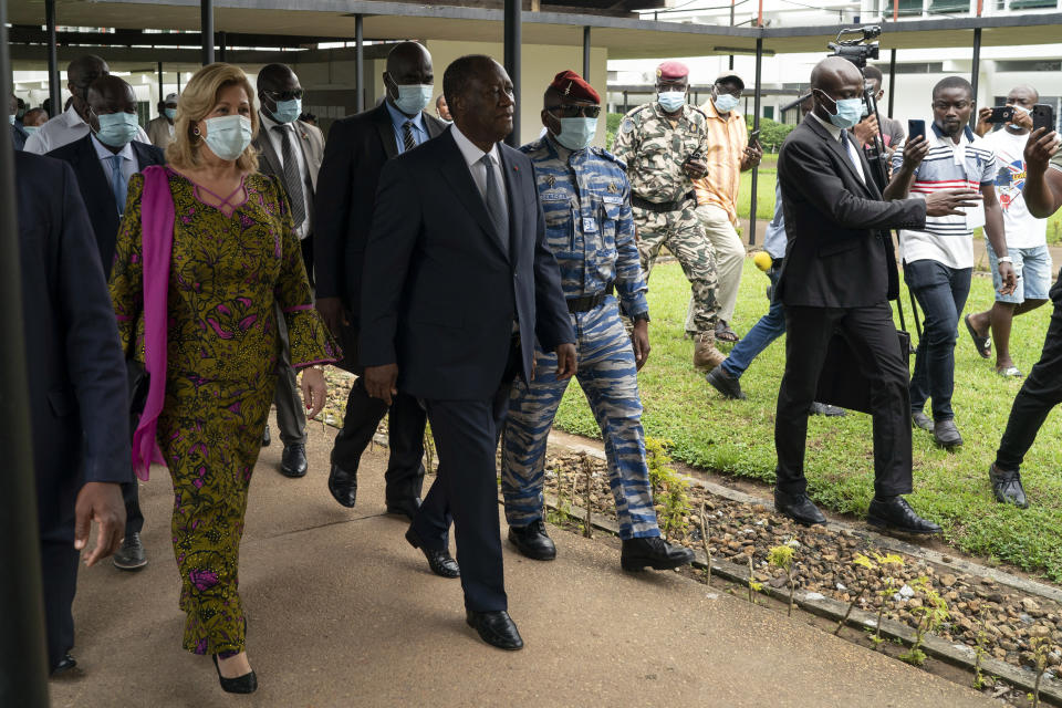 Ivory Coast President Alassane Ouattara, center, and his wife Dominique Ouattara, left, leave after voting in a polling station during presidential elections in Abidjan, Ivory Coast, Saturday, Oct. 31, 2020. Tens of thousands of security forces deployed across Ivory Coast on Saturday as the leading opposition parties boycotted the election, calling President Ouattara's bid for a third term illegal. (AP Photo/Leo Correa)