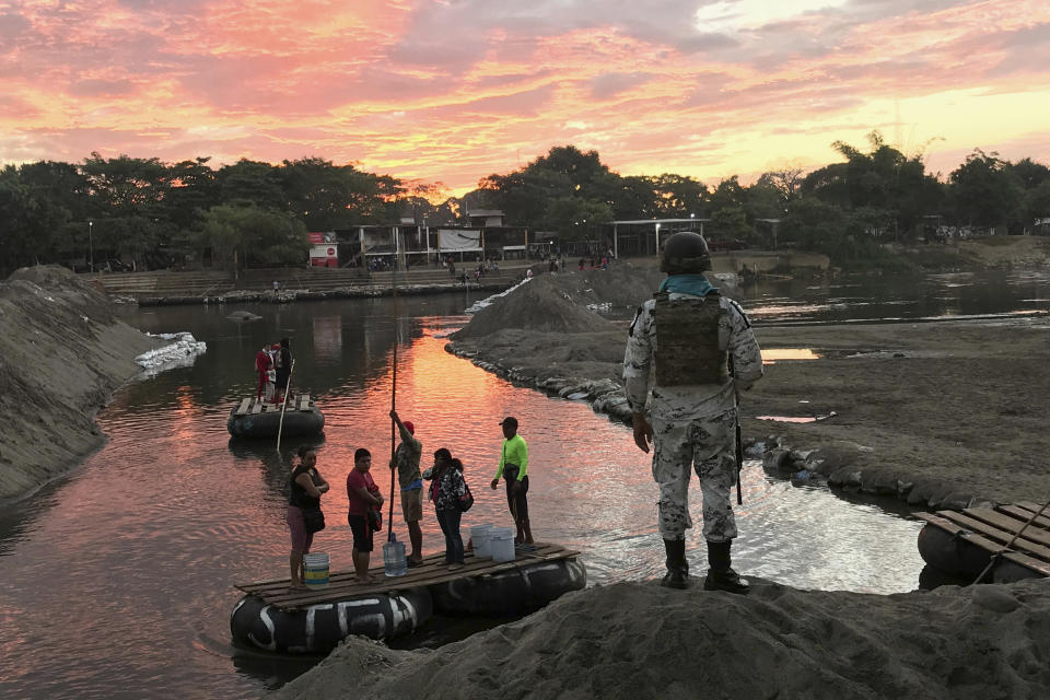 Un miembro de la Guarda Nacional de México mira mientras residentes cruzan el río Suchiate, cerca de Ciudad Hidalgo, en la frontera con Guatemala, el 17 de enero de 2020. (AP Foto/Maria Verza)