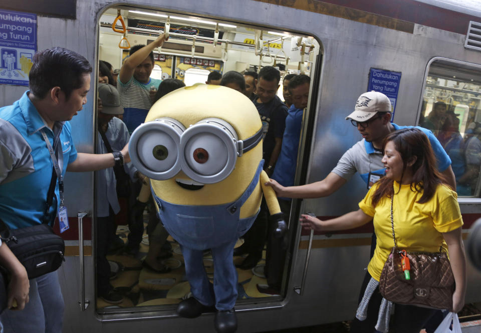 FILE - A performer dressed as Bob the Minion, from the "Despicable Me" franchise, steps off a train during a promotional event in Jakarta, Indonesia on June 12, 2015. This summer, the goggle-wearing yellow ones will return in “Minions: Rise of Gru," in theaters July 1. The “Despicable Me” franchise and its “Minions” spinoffs are the highest grossing animated film franchise ever with more than $3.7 billion in tickets sold worldwide. (AP Photo/Dita Alangkara, File)