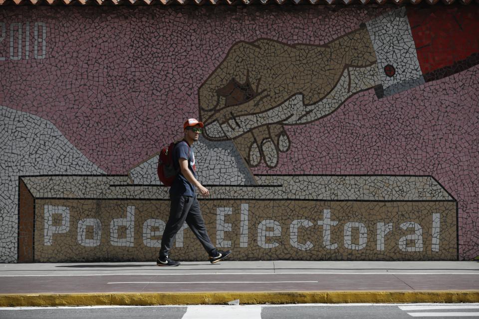 Un hombre camina junto a un mural que representa una urna, frente a la sede del Consejo Nacional Electoral en Caraca, Venezuela, el miércoles 31 de julio de 2024, tres días después de que el país enfrentara una controvertida elección presidencia. (AP Foto/Cristian Hernández)