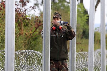 A Hungarian army soldier gestures as others build a fence on the border with Croatia near Sarok, Hungary, September 20, 2015. REUTERS/Bernadett Szabo