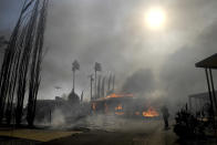 Firefighters battle the Sandalwood Fire as it destroys homes in the Villa Calimesa Mobile Home Park in Calimesa, Calif., on Thursday, Oct. 10, 2019. Burning trash dumped along a road sparked a wildfire Thursday that high winds quickly pushed across a field of dry grass and into a Southern California mobile home park, destroying dozens of residences. (Jennifer Cappuccio Maher/The Orange County Register/SCNG via AP)