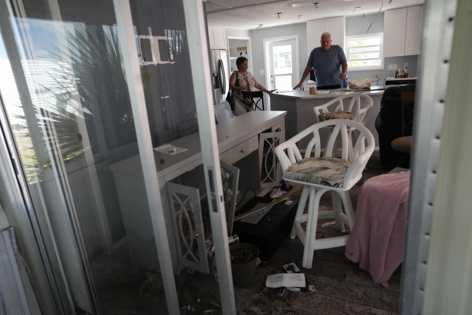 Robert Burton, right, and his partner Cindy Lewis, both 71, visit their damaged home, still full of waterlogged furniture and belongings, in the Century 21 mobile home community in Fort Myers, Fla., Tuesday, May 2, 2023. Hurricane Ian flood waters reached several feet above the raised floor level and even shifted several homes from their foundations. "No one has a home. That park will not be reopened as a residential community," Lewis said. "So everybody lost." (AP Photo/Rebecca Blackwell)