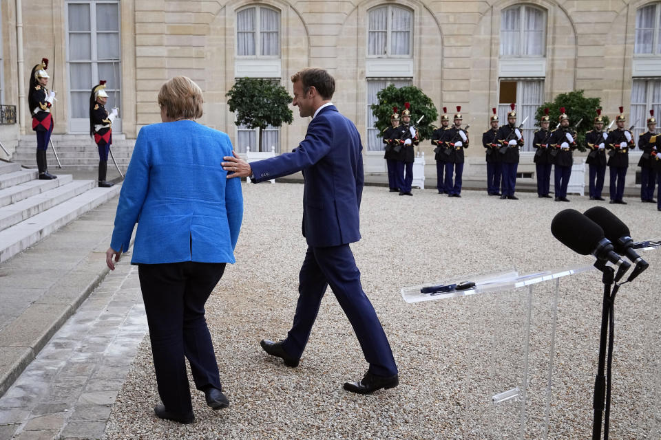 France's President Emmanuel Macron, right, and German Chancellor Angela Merkel leave after a joint press conference, at the Elysee Palace, in Paris, Thursday, Sept. 16, 2021. (AP Photo/Michel Euler)