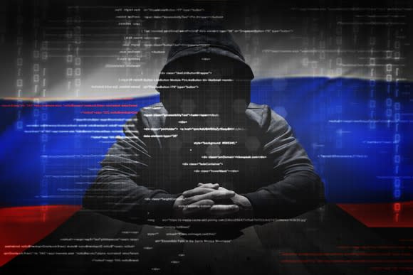 A hacker in front of a Russian flag.