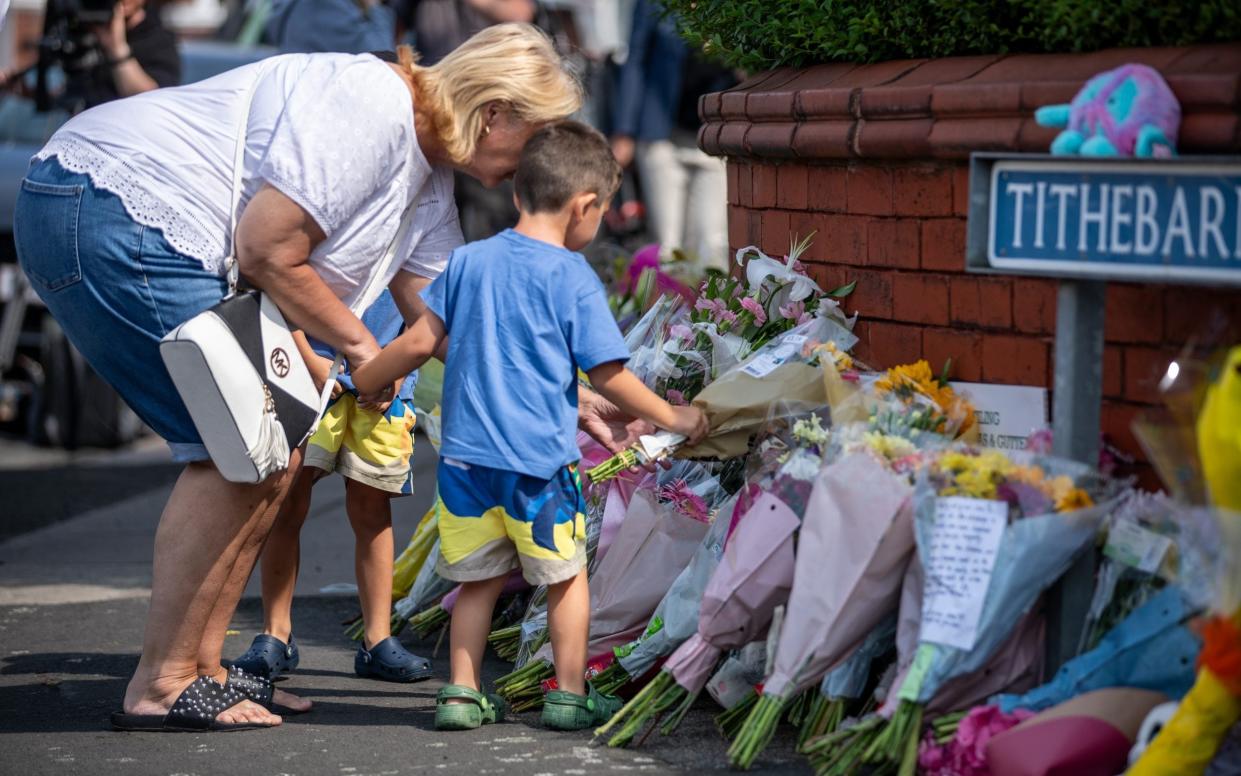 Children and adults leave boquets of flowers