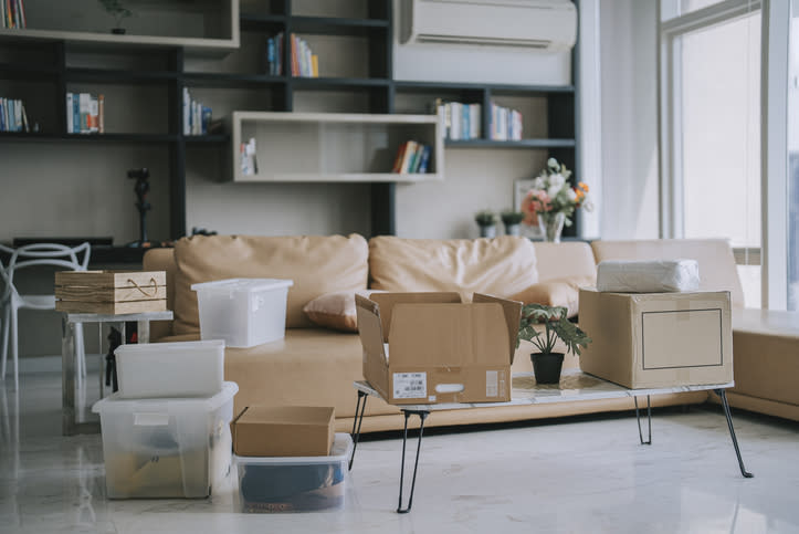 Living room with moving boxes and furniture, indicating packing or unpacking for relocation