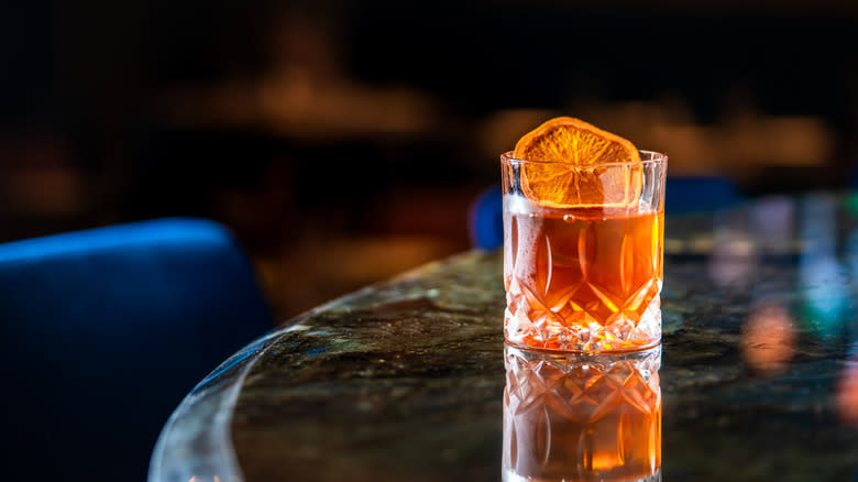 whiskey cocktail with orange wheel