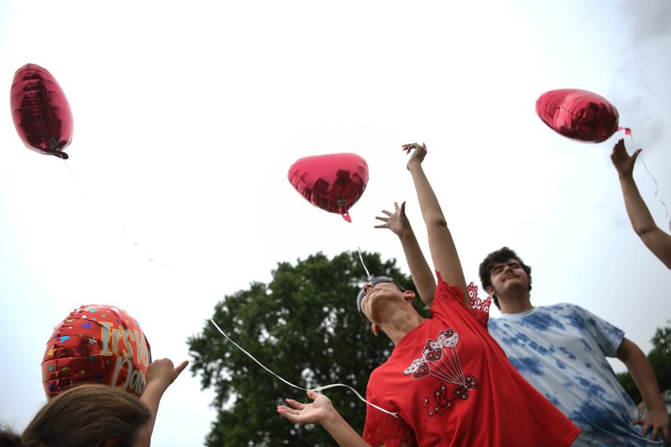 Jennifer Byrum, surrounded by family, releases balloons in her father Ricky Lewis' memory on the one-year anniversary of his death, May 26.