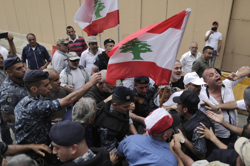 Police scuffle with Lebanese retired soldiers during a protest in front of the government building during a cabinet meeting to discuss an austerity budget, in Beirut, Lebanon, Friday, May 10, 2019. Dozens of Lebanese military and security veterans burned tires and shouted angrily outside government offices on Friday, their second protest in less than two weeks amid fears a proposed austerity budget may affect their pensions and benefits. (AP Photo/Hassan Ammar)