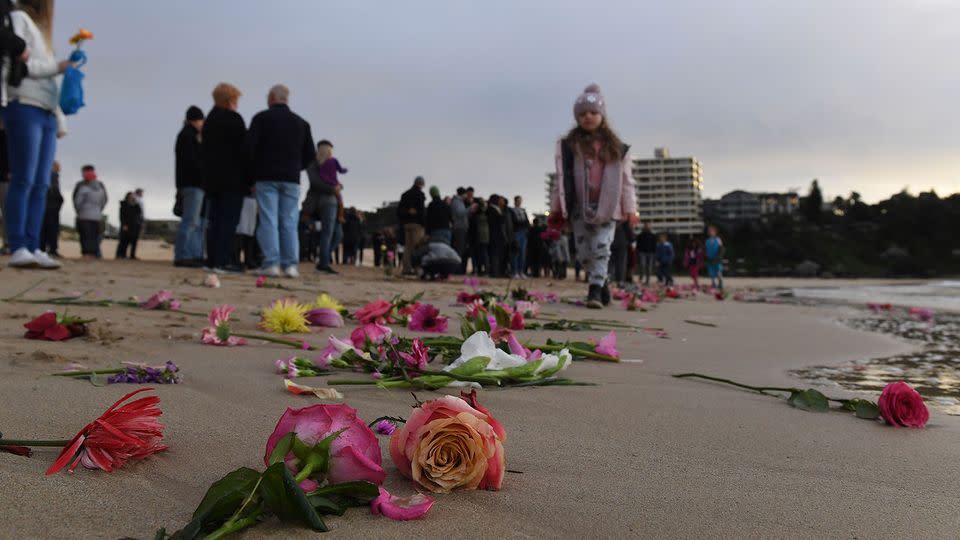 Those attending the vigil were asked to bring pink flowers to lay on the beach. Photo: AAP