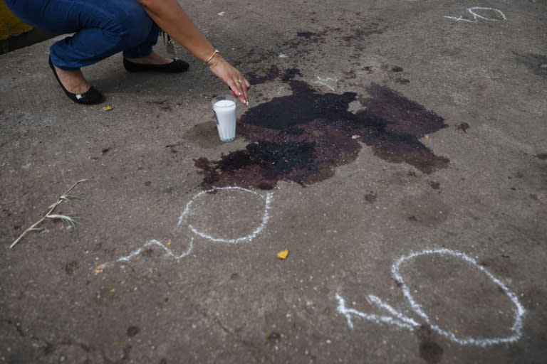 A relative places a candle beside the pool of dried blood where Mexican journalist Candido Rios was killed in Hueyapan de Ocampo, Veracruz state -- he was the 10th journalist murdered in Mexico this year