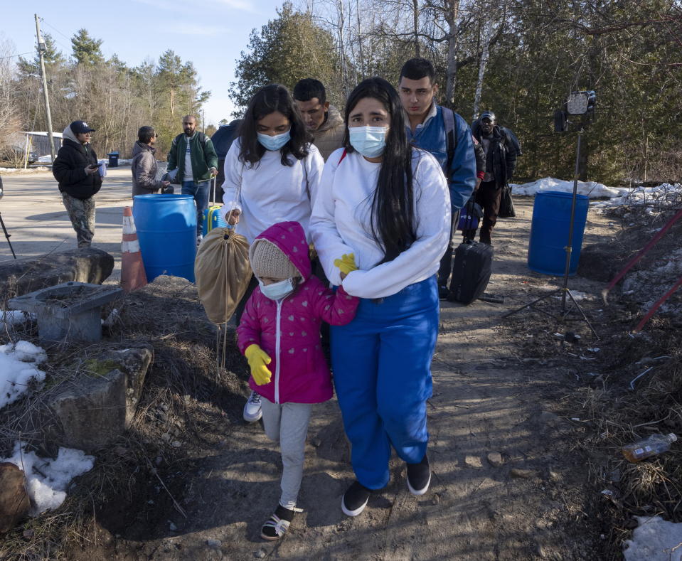 Asylum seekers cross the border at Roxham Road from New York into Canada on Friday, March 24, 2023 in Champlain, N.Y. The irregular border crossing will be closed permanently tonight at midnight. (Ryan Remiorz/The Canadian Press via AP)