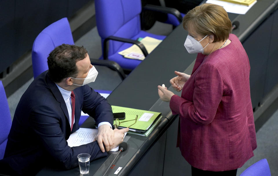 German Chancellor Angela Merkel, right, talks to German Health Minister Jens Spahn, left, during a meeting of the German federal parliament, Bundestag, at the Reichstag building in Berlin, Germany, Wednesday, April 21, 2021. (AP Photo/Michael Sohn)