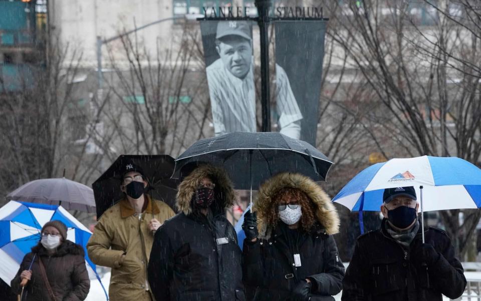 People line up in the rain and snow outside the Yankee Stadium - TIMOTHY A. CLARY/AFP