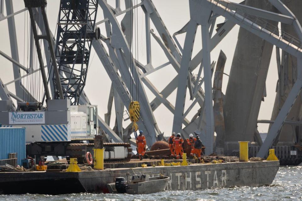BALTIMORE, MARYLAND - MARCH 30: Debris is cleared from the collapsed Francis Scott Key Bridge as efforts begin to reopen the Port of Baltimore on March 30, 2024, in Baltimore, Maryland. The bridge, which was used by roughly 30,000 vehicles each day, fell into the Patapsco River after being struck by the Dali, a cargo ship leaving the port at around 1:30am on Tuesday morning. The bodies of two men who were on the bridge at the time of the accident have been recovered from the water; four others are still missing and presumed dead; two others were rescued and treated for injuries shortly after the accident. The Port of Baltimore is one of the largest and busiest ports on the East Coast of the U.S. (Photo by Scott Olson/Getty Images)