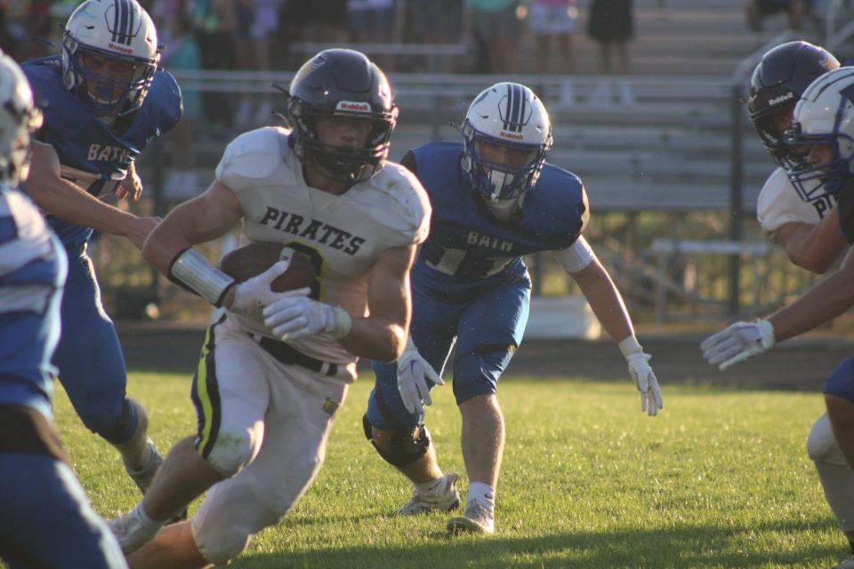 Pewamo-Westphalia junior running back Brayton Thelen (No. 3) carries the ball while Bath senior linebacker Andrew Raphael (No. 11) chases him during a varsity football game Thursday, Aug. 31, at Bath High School. P-W won the game, 21-0.