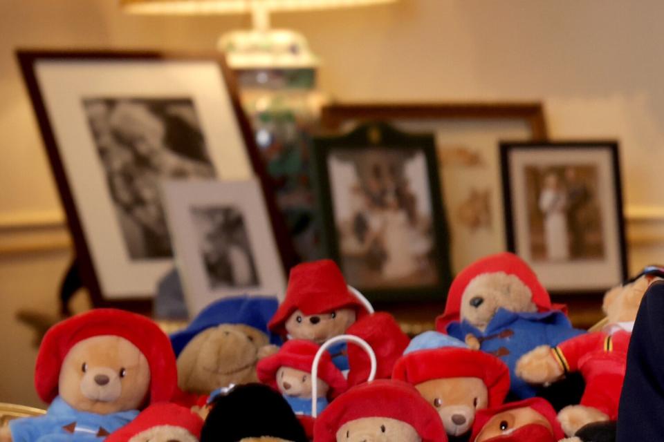 In this handout image issued by Buckingham Palace, Camilla, Queen Consort, poses with a collection of Paddington cuddly toys in the Morning Room at Clarence House