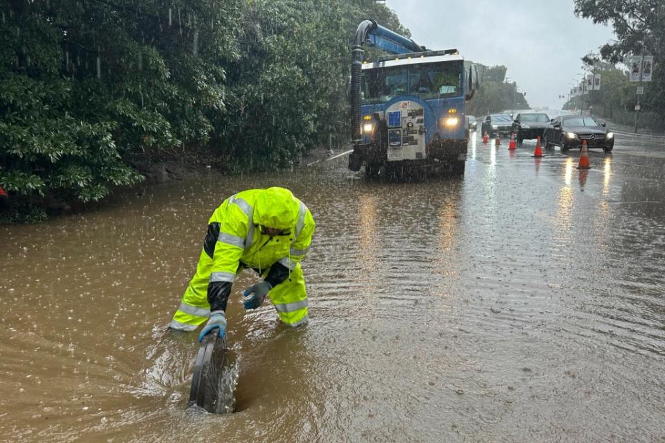 A whirlpool forms around a city worker in the Holmby Hills neighborhood of Los Angeles as he lifts a manhole cover to clear street flooding. AP