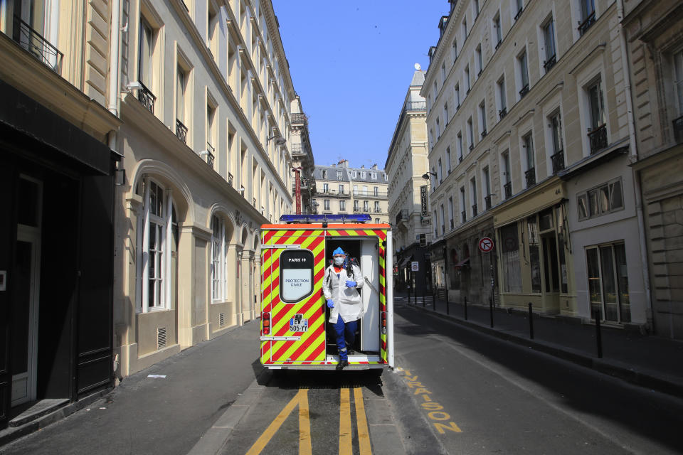 In this photo taken Saturday March 28, 2020, Cyril Lamriben, a member of the Civil Protection service, steps out of an ambulance on his way to check a woman possibly infected with the Covid-19 virus in Paris. They don't have to put themselves in harm's way, but the volunteers of France's well-known Civil Protection service choose the front line in the fight against the coronavirus. They are often the first to knock on the doors of people calling for help, and who may have the infection or whose confirmed case has taken a downturn. (AP Photo/Michel Euler)