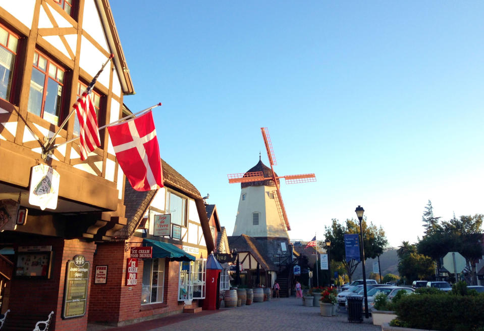 FILE - This Sept. 30, 2014 photo shows the Danish flag flying on Alisal Road in Solvang, Calif., on Sept. 30, 2014. Founded in 1911 by Danish immigrants, Solvang is a touristy enclave with Danish bakeries, Danish-themed hotels and even a Hans Christian Andersen Museum. The location is featured in a collection of mini-essays by American writers published online by the Frommer's guidebook company about places they believe helped shape and define America. (AP Photo/Solvej Schou, File)