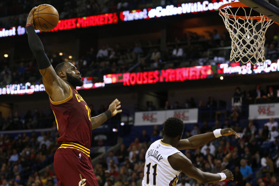 Cleveland Cavaliers forward LeBron James, left, dunks the ball over New Orleans Pelicans guard Jrue Holiday (11) during the first half of an NBA basketball game, Monday, Jan. 23, 2017, in New Orleans. (AP Photo/Jonathan Bachman)
