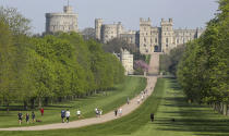 People exercise social distancing as they take their exorcise on the Long Walk in front of Windsor Castle during the Easter bank holiday weekend, as the UK continues in lockdown to help curb the spread of the coronavirus, in Windsor, England, Friday April 10, 2020. The highly contagious COVID-19 coronavirus has impacted on nations around the globe, many imposing self isolation and exercising social distancing when people move from their homes. (Steve Parsons / PA via AP)