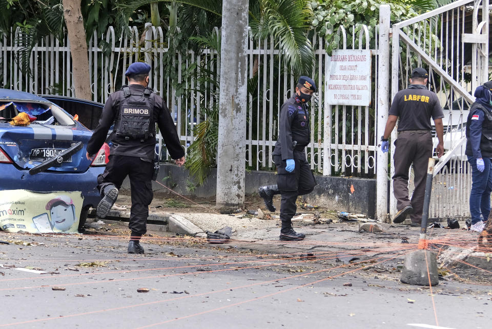 Police investigators collect evidence from around the site of a bomb attack at the Sacred Heart of Jesus Cathedral in Makassar, South Sulawesi, Indonesia, Monday, March 29, 2021. Two attackers believed to be members of a militant network that pledged allegiance to the Islamic State group blew themselves up outside the packed Roman Catholic cathedral during a Palm Sunday Mass on Indonesia's Sulawesi island, wounding a number of people, police said. (AP Photo/Masyudi S. Firmansyah)