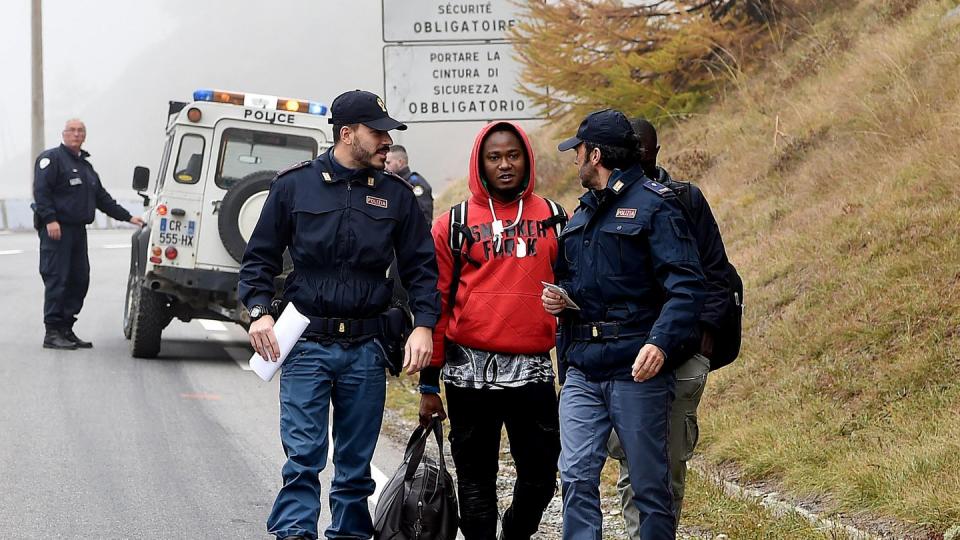 Italienische Polizisten überprüfen einen Mann nahe der Grenze zu Frankreich. Foto: Alessandro Di Marco/ANSA/AP