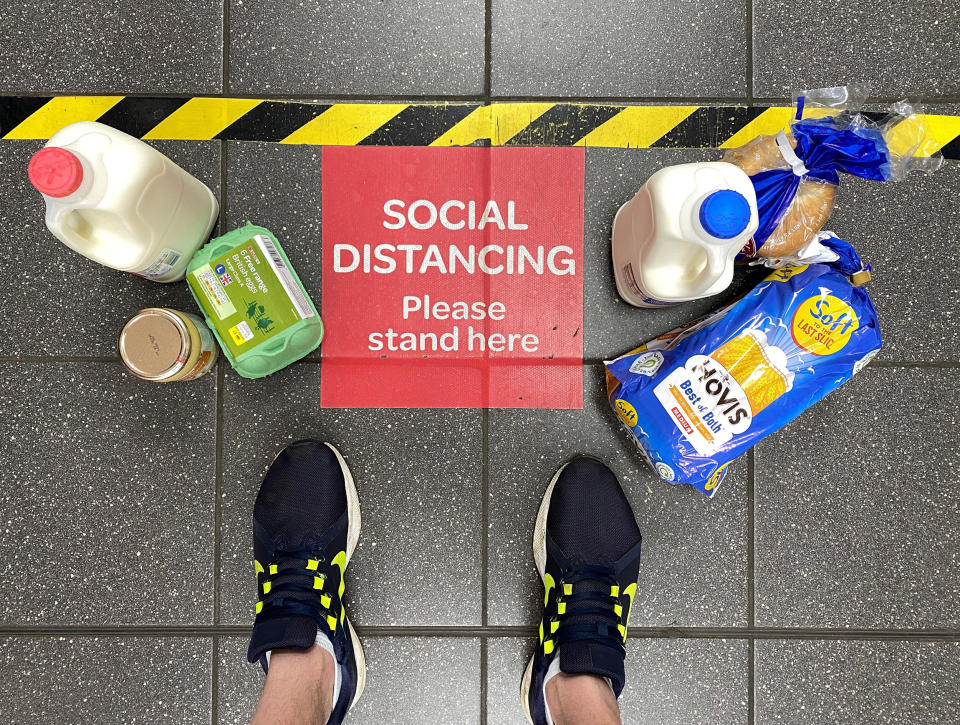 Image: Food shopping next to a social distancing sign at a British supermarket in April. (Paul Child / Reuters file)