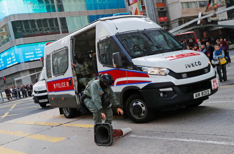 A riot police officer removes a traffic cone thrown by a protester to block the traffic, outside Mong Kok station in Hong Kong