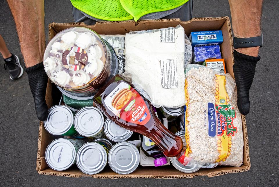 A volunteer holds a box of food at the Greenbank Church of Christ drive-thru food pantry in Prices Corner on Thursday, Aug. 25, 2022. The pantry serves free meals to the community and continues to follow COVID-19 protocols.