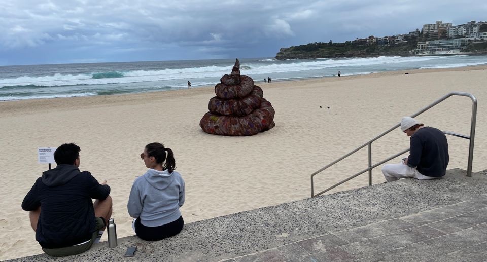 People sitting on the stairs in front of the giant poo.