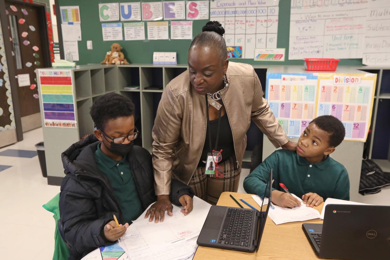 Fifth grade teacher Anita Jones checks in on the work of students Tristan May, left, and Arkey Green, right, as they work on a lesson on 'Creating Your Own Civilization' in their class at Dr. Walter Cooper Academy School No.10 in Rochester Thursday, Dec. 8, 2022.