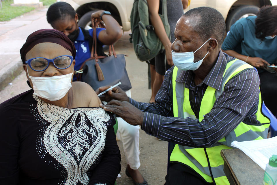 FILE - A woman receives a coronavirus vaccine in Abuja, Nigeria, Monday, Nov 29, 2021. A pandemic-weary world faces weeks of confusing uncertainty as countries restrict travel and take other steps to halt the newest potentially risky coronavirus mutant before anyone knows just how dangerous omicron really is. (AP Photo/Gbemiga Olamikan, File)