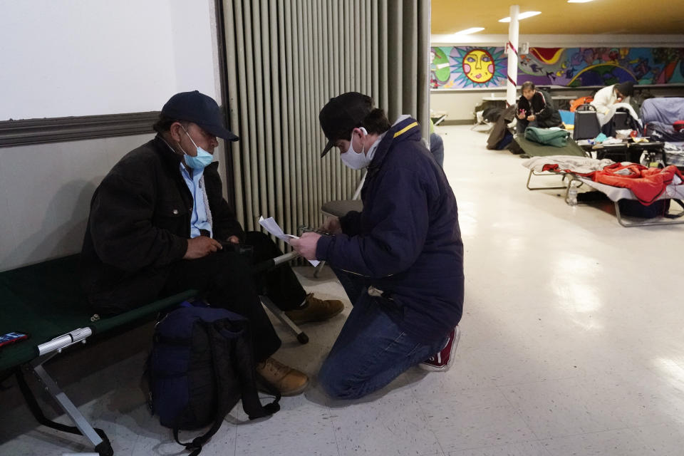 Pastor Gavin Rogers, right, works with Alberto, left, who was moved to a warming shelter to escape sub-freezing temperatures at Travis Park Methodist Church, Tuesday, Feb. 16, 2021, in San Antonio. (AP Photo/Eric Gay)