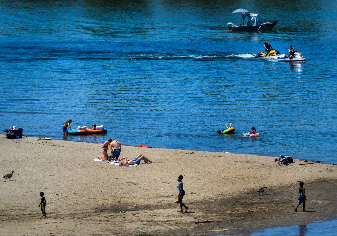 Groups of people enjoy the water at Tiscornia Beach in Sacramento in May 2020. The beach, at the confluence of the American and Sacramento rivers, is a popular swimming area.