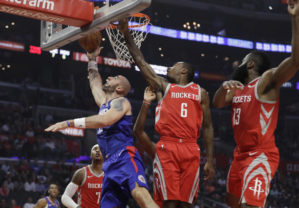 Los Angeles Clippers' Marcin Gortat, left, scores past Houston Rockets' Gary Clark (6) and James Harden (13) during the first half of an NBA basketball game Sunday, Oct. 21, 2018, in Los Angeles. (AP Photo/Marcio Jose Sanchez)