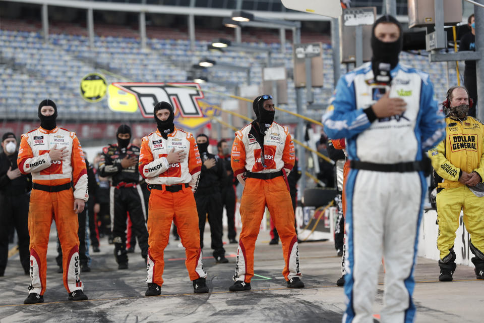 Crew members stand during the national anthem before a NASCAR Truck Series auto race at Charlotte Motor Speedway Tuesday, May 26, 2020 in Concord, N.C. (AP Photo/Gerry Broome)