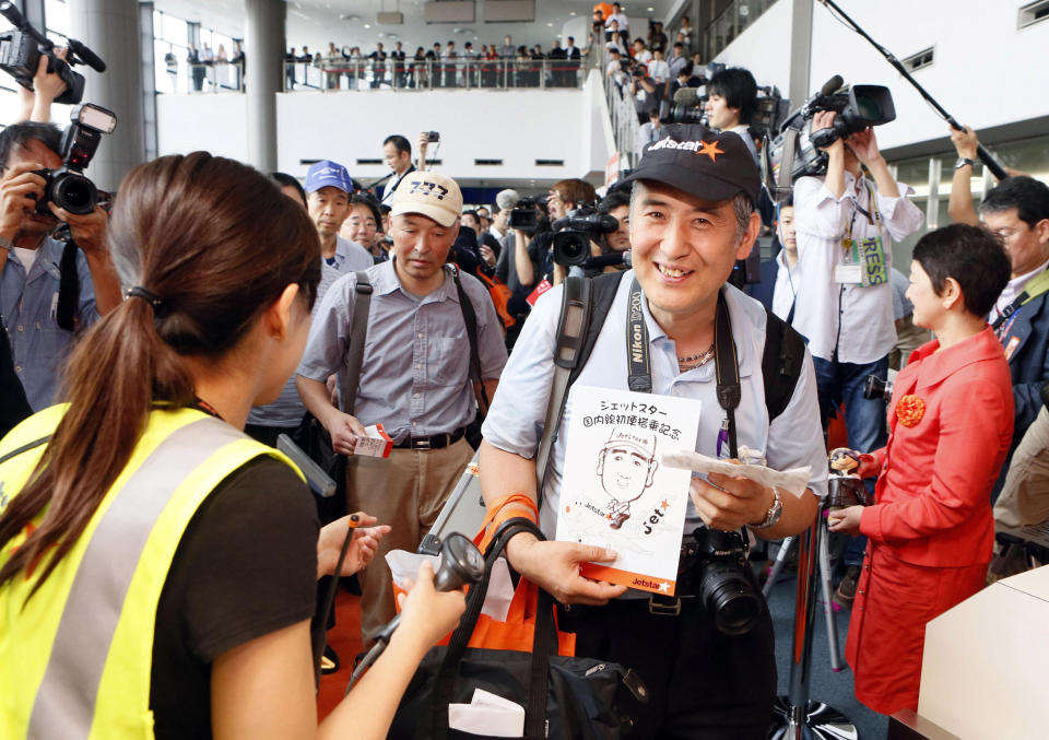 In this July 3, 2012 file photo, passengers prepare to board the first flight by Jetstar Japan at Narita International Airport in Narita near Tokyo. Japan has a reputation for loving expensive things like overpriced real estate, gourmet melons and luxury brands. But the nation is finally discovering the joy of flying cheap, with the arrival this year of three low-cost carriers. The takeoff of AirAsia Japan, Peach Aviation and Jetstar Japan could change lifestyles. (AP Photo/Kyodo News, File) JAPAN OUT, MANDATORY CREDIT, NO LICENSING IN CHINA, FRANCE, HONG KONG, JAPAN AND SOUTH KOREA