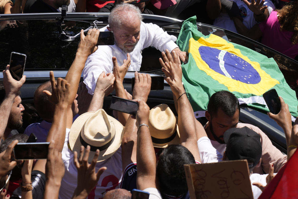 Former Brazilian President Luiz Inacio Lula da Silva, center, who is running for president again, hold hands with a supporter after voting in a presidential run-off election in Sao Paulo, Brazil, Sunday, Oct. 30, 2022. (AP Photo/Andre Penner)