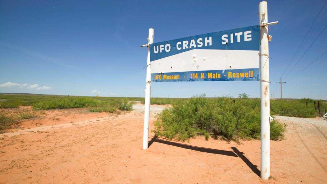  A sign in the desert that reads "ufo crash site, ufo museum 114 north main street, roswell". 