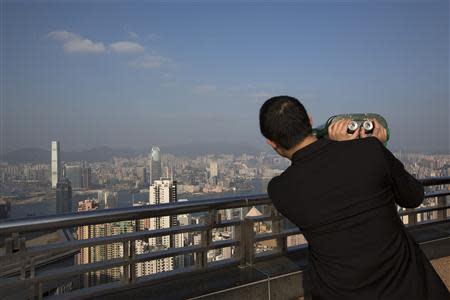 A mainland Chinese businessmen views the Hong Kong skyline with binoculars at the Peak in Hong Kong January 14, 2014. REUTERS/Tyrone Siu