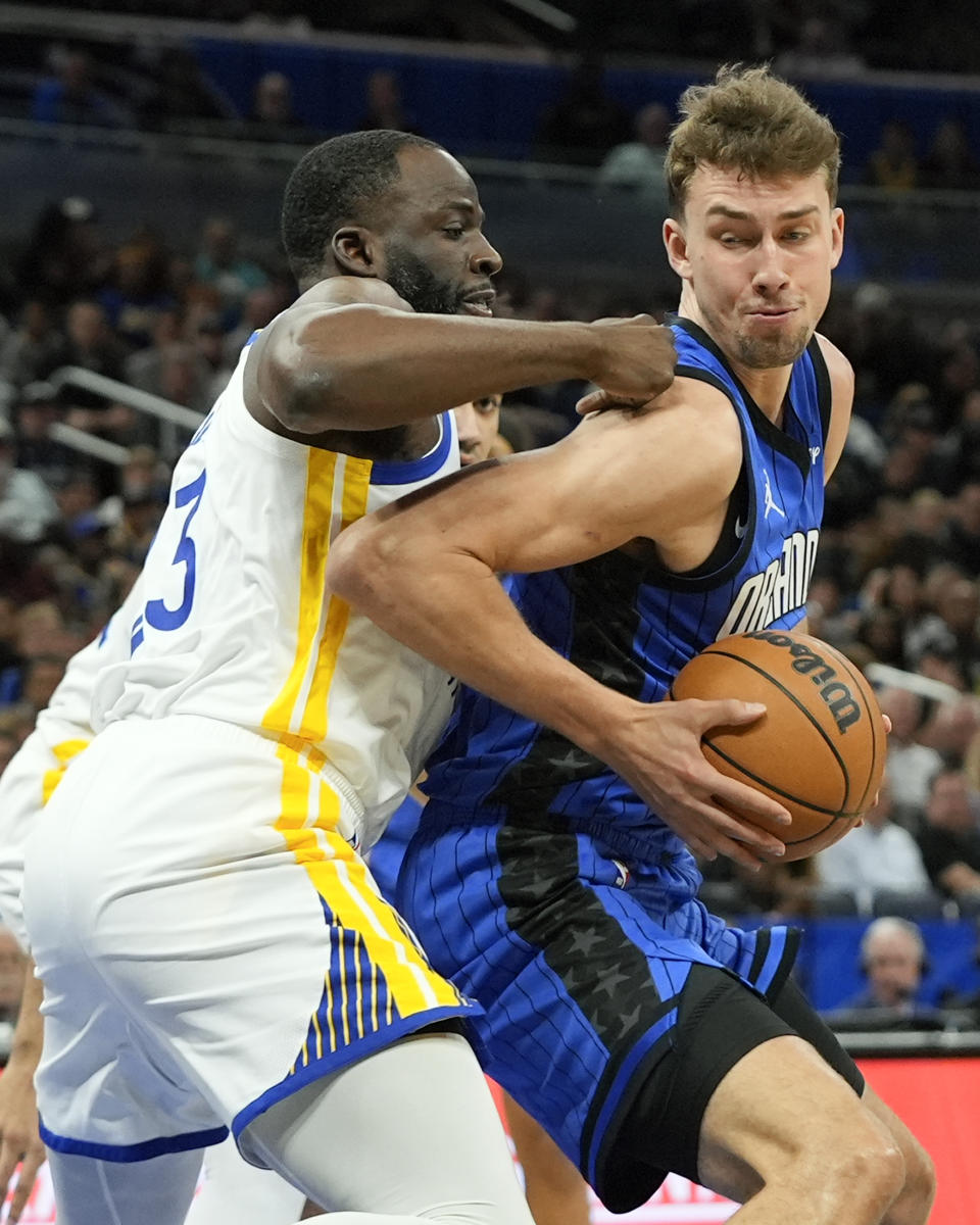 Orlando Magic forward Franz Wagner, right, makes a move to get past Golden State Warriors forward Draymond Green during the first half of an NBA basketball game Wednesday, March 27, 2024, in Orlando, Fla. (AP Photo/John Raoux)