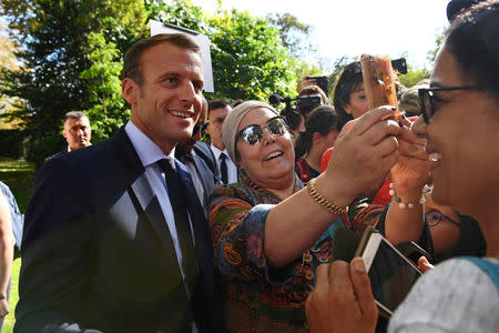 FILE PHOTO: French President Emmanuel Macron poses for a selfie with a woman as visitors are allowed access to the Elysee Palace in Paris, France, September 15, 2018, as part of France's Heritage Days. Anne-Christine Poujoulat/Pool via REUTERS/File Photo