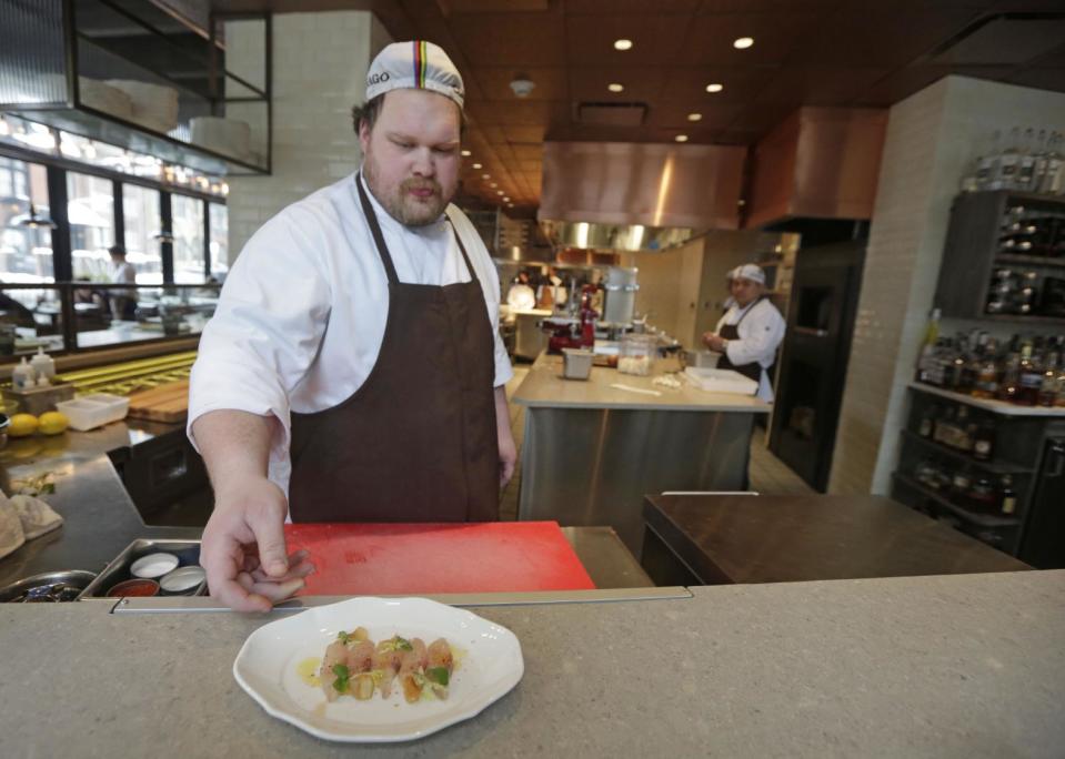 This Feb. 12, 2014, shows lunch cook Jarrod Storbeck with a finished dish of Kanpachi at chef Paul Kahan's restaurant Nico Osteria in Chicago. Kahan is executive chef and one of the owners of One Off Hospitality, working together with his partners _ including Donnie Madia, nominated for best restaurateur in this year’s Beard Awards _ to run seven restaurants in Chicago. He counts among his fans Anthony Bourdain and first lady Michelle Obama, and last year shared the Beard Award for best chef with New York’s David Chang, the man behind the Momofuko restaurants.(AP Photo/M. Spencer Green)